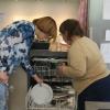 une personne handicapée range la vaisselle avec une assistante